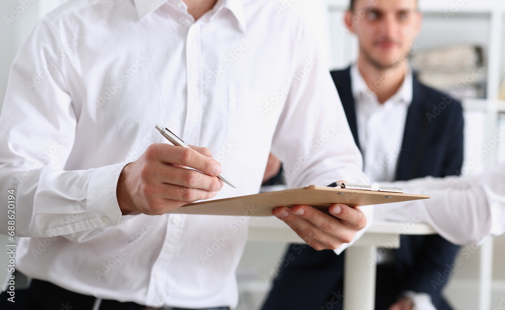 Male arm in shirt hold silver pen and pad making note in office closeup. Deal consult delivery signature financial inspector job fill survey form discuss strategy project negotiation concept Male arm in shirt hold silver pen and pad making note in office closeup. Deal consult delivery signature financial inspector job fill survey form discuss strategy project negotiation concept