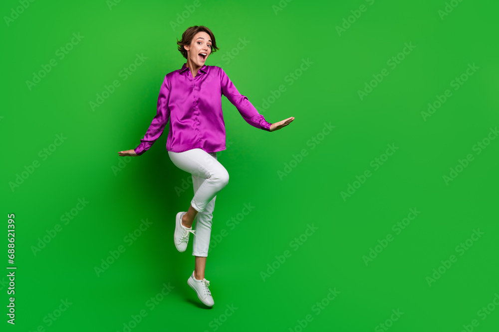 Full body portrait of astonished pretty lady jumping empty space offer proposition isolated on green color background