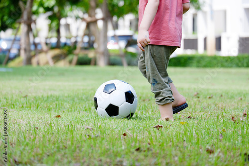 A boy runs and kicks football in the grass. © krongthip