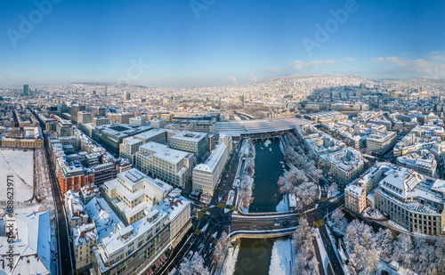 Aerial View of Zurich's Central Station Area with Snow-Covered Buildings and Shopping District in December, Sunlit After Snowfall.