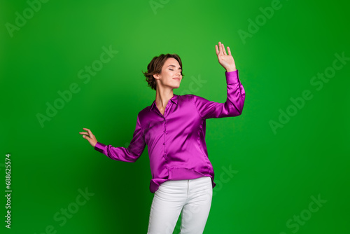 Portrait of cheerful pretty person raise hands closed eyes enjoy dancing chilling isolated on green color background