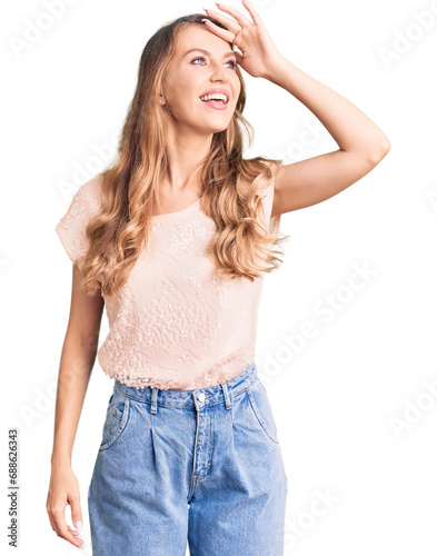Young beautiful caucasian woman with blond hair wearing casual clothes very happy and smiling looking far away with hand over head. searching concept.