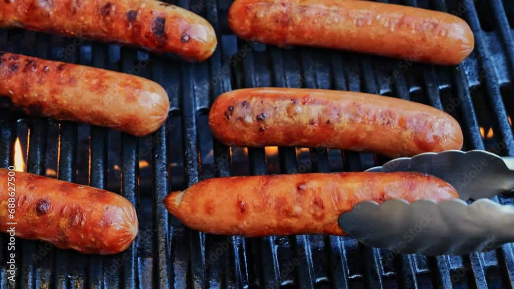 Grilled sausages Bockwurst on barbecue grill grate, flame. Turn the sausages over. Close up. Slow motion. Grilled sausages Bockwurst on barbecue grill grate, flame. Turn the sausages over. Close up. Slow motion.