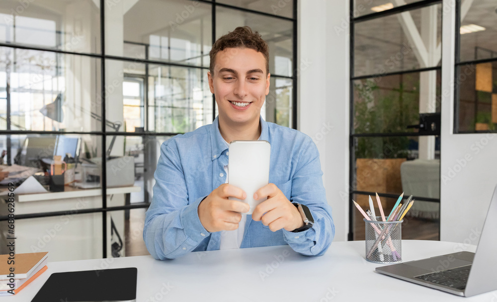 Smiling attractive millennial caucasian guy manager with laptop at table chatting Smiling attractive millennial caucasian guy manager with laptop at table chatting