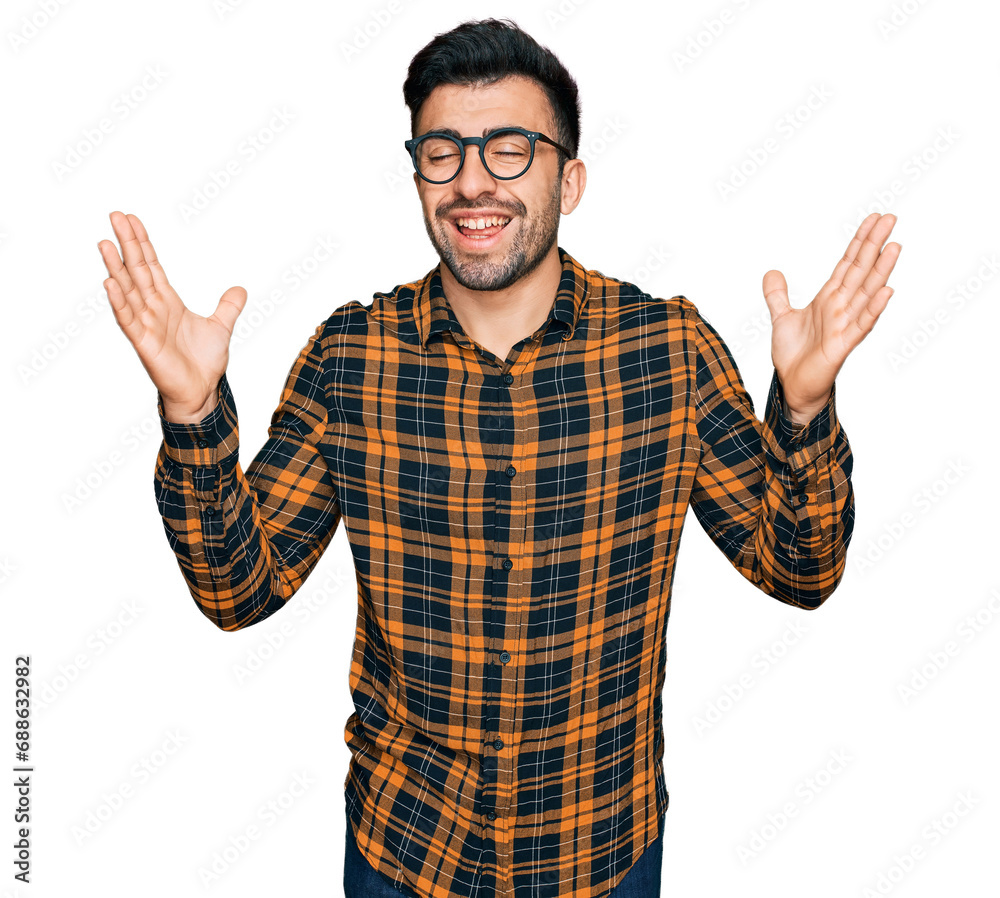 Hispanic man with beard wearing casual clothes and glasses celebrating mad and crazy for success with arms raised and closed eyes screaming excited. winner concept Hispanic man with beard wearing casual clothes and glasses celebrating mad and crazy for success with arms raised and closed eyes screaming excited. winner concept