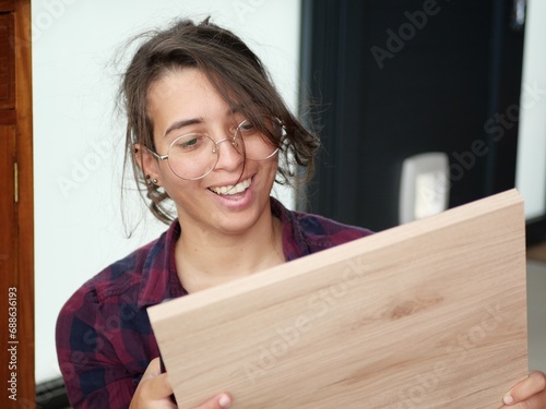 Femme souriante tenant dans ses mains une planche de bois pour faire du bricolage