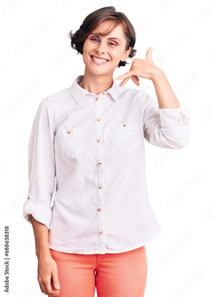 Beautiful young woman with short hair wearing elegant white shirt smiling doing phone gesture with hand and fingers like talking on the telephone. communicating concepts. Beautiful young woman with short hair wearing elegant white shirt smiling doing phone gesture with hand and fingers like talking on the telephone. communicating concepts.