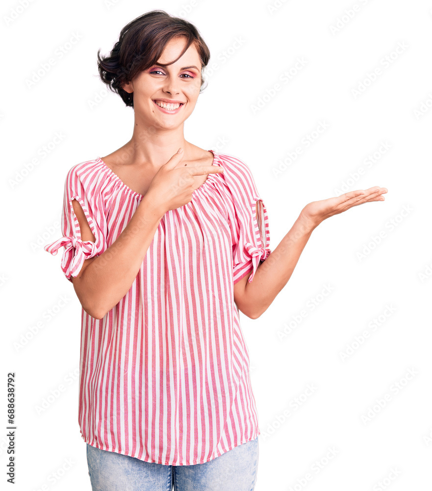 Beautiful young woman with short hair wearing casual summer clothes amazed and smiling to the camera while presenting with hand and pointing with finger.
