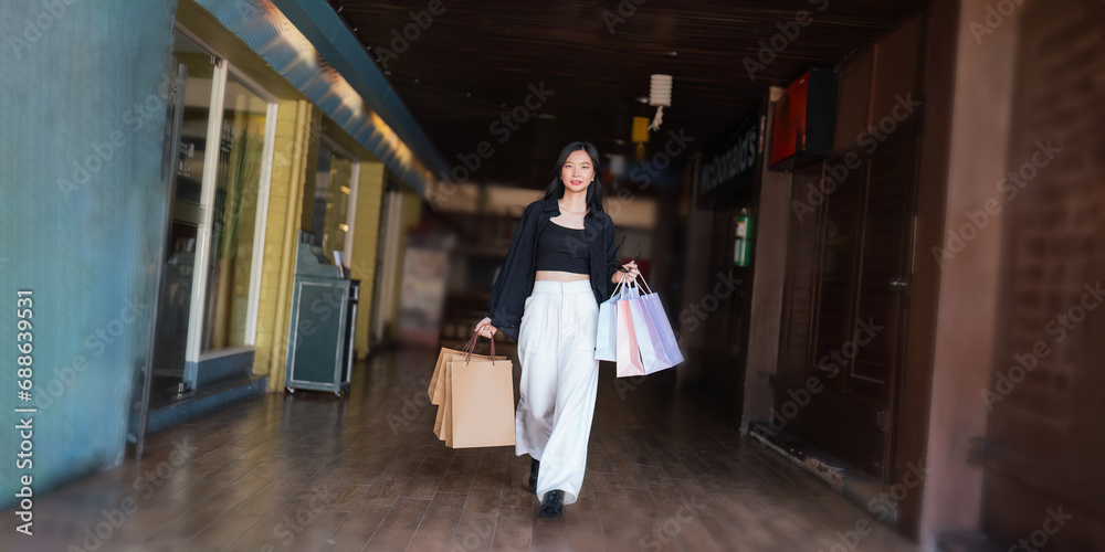 Fototapeta premium Happy beautiful young stylish woman asian with shopping bag while walking in the mall on holiday Black Friday