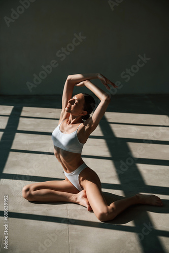 Fitness woman in white clothes is indoors in sunlight