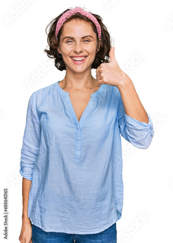 Young hispanic woman wearing casual clothes smiling happy and positive, thumb up doing excellent and approval sign