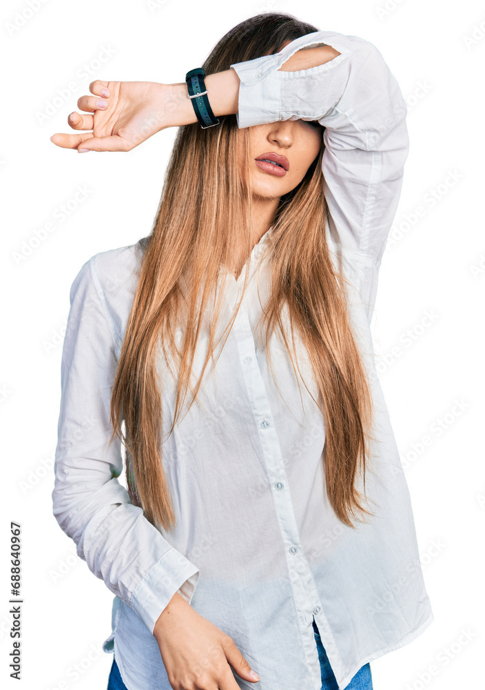 Beautiful caucasian woman wearing casual white shirt covering eyes with arm, looking serious and sad. sightless, hiding and rejection concept Beautiful caucasian woman wearing casual white shirt covering eyes with arm, looking serious and sad. sightless, hiding and rejection concept