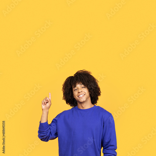 Look Up. Cheerful Black Guy Pointing Finger Up At Copy Space © Prostock-studio