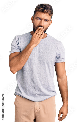 Young hispanic man wearing casual clothes bored yawning tired covering mouth with hand. restless and sleepiness.