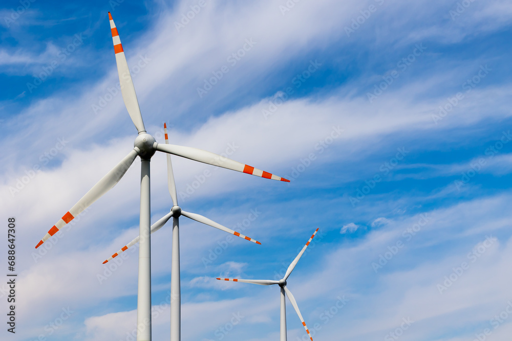 Fototapeta premium Wind turbine rotors against the blue sky. Green electricity production. Photo taken on a sunny day.
