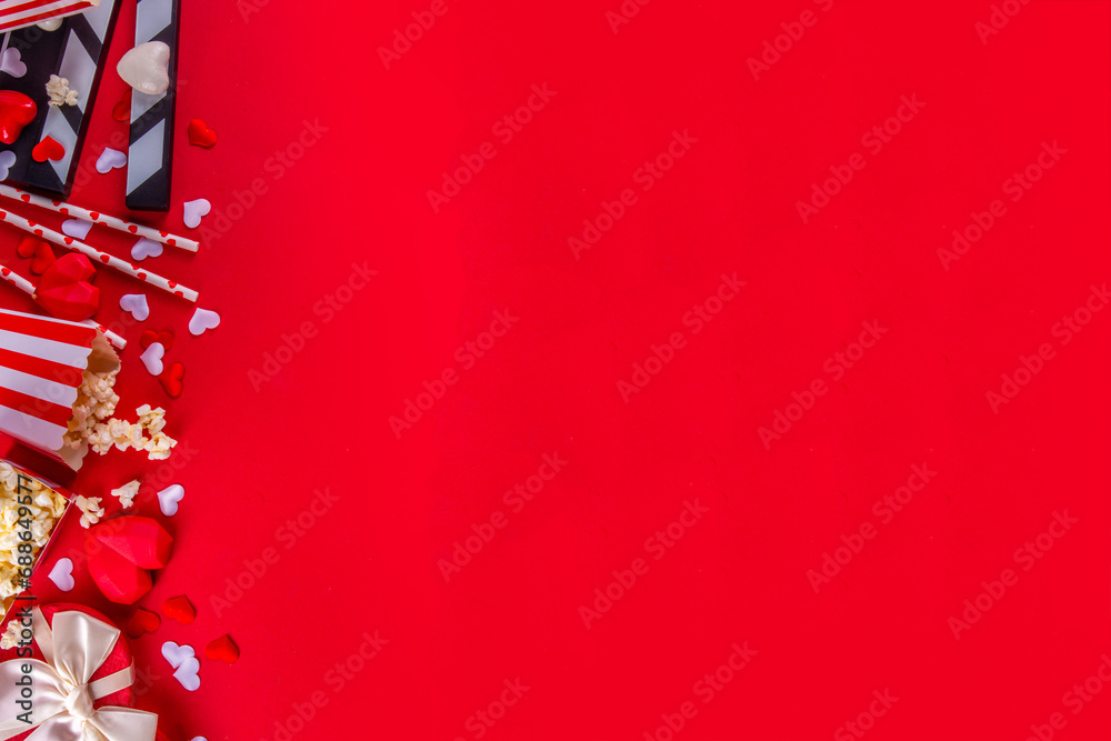 Romantic date on Valentine's Day February 14. Love movie marathon, date at cinema theater. Clapperboard, popcorn buckets, heart decor and chocolates on red background flat lay copy space Romantic date on Valentine's Day February 14. Love movie marathon, date at cinema theater. Clapperboard, popcorn buckets, heart decor and chocolates on red background flat lay copy space