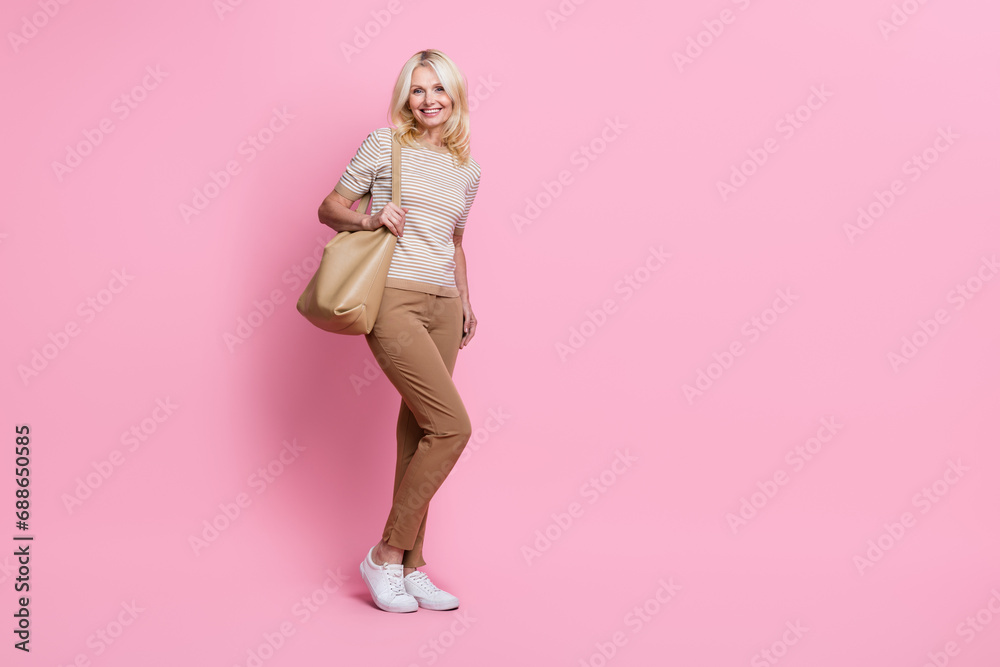 Full length photo of pretty cheerful person hold handbag empty space ad offer isolated on pink color background