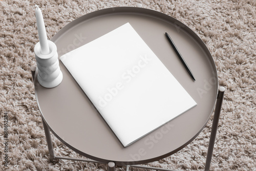 Magazine mockup with a candle on the beige table. photo