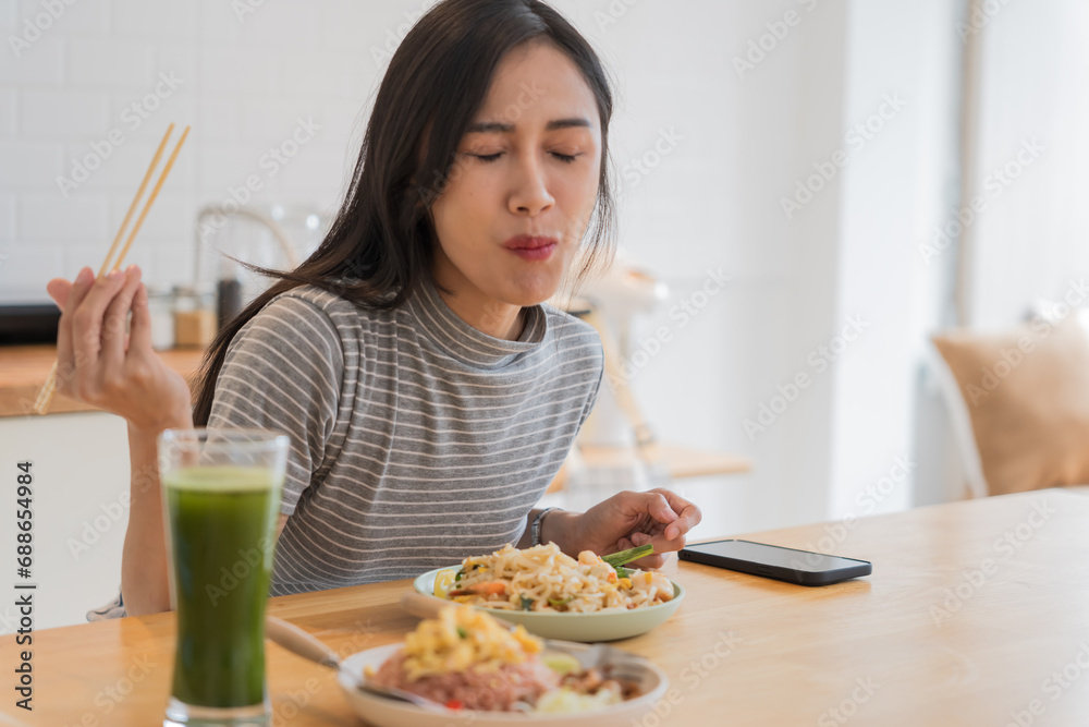 Asian Girl eating Thai food in kitchen counter Home delivery food feeling happy Asian Girl eating Thai food in kitchen counter Home delivery food feeling happy