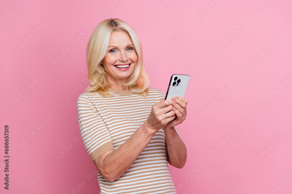 Photo of cheerful nice lady beaming smile hold smart phone typing post empty space isolated on pink color background Photo of cheerful nice lady beaming smile hold smart phone typing post empty space isolated on pink color background
