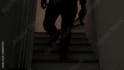 Mysterious man wearing black hoodie holding a pistol wearing a cloth mask covering his face completely in front of the door, Silhouette and dark concept image,threat of firearms,attack or defense. photo