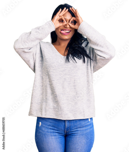 Hispanic woman with long hair wearing casual clothes doing ok gesture like binoculars sticking tongue out, eyes looking through fingers. crazy expression. © Krakenimages.com