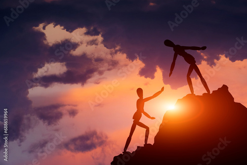 Two silhouettes mannequin climb mountain, one helping other, extending helping hand. Against background sky, sunset and clouds. Concept of help and success in teamwork.