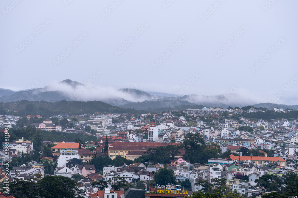 Obraz premium View on roofs in the city of Dalat. Da Lat and the surrounding area is a popular tourist destination of Asia. City with fogs and mountains