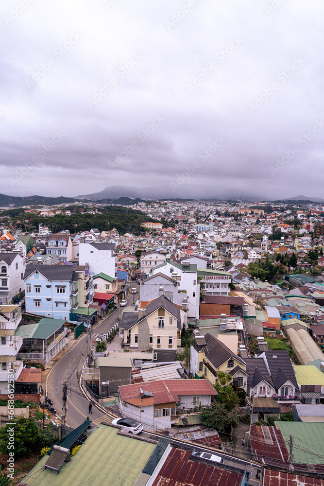 Fototapeta premium View on roofs in the city of Dalat. Da Lat and the surrounding area is a popular tourist destination of Asia. City with fogs and mountains
