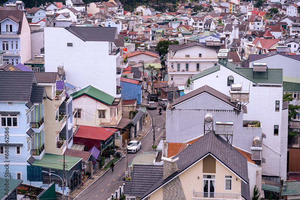 Fototapeta premium View on roofs in the city of Dalat. Da Lat and the surrounding area is a popular tourist destination of Asia. City with fogs and mountains