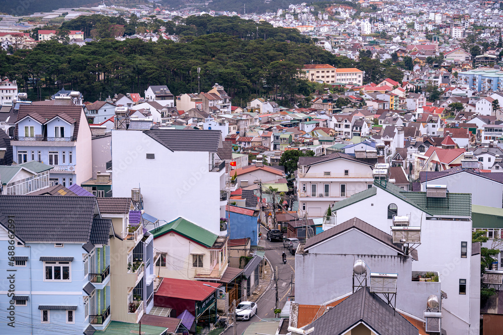 Fototapeta premium View on roofs in the city of Dalat. Da Lat and the surrounding area is a popular tourist destination of Asia. City with fogs and mountains