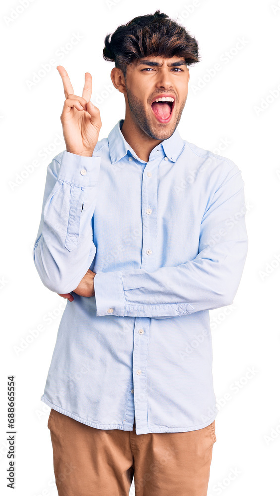 Young hispanic man wearing casual shirt smiling with happy face winking at the camera doing victory sign. number two. Young hispanic man wearing casual shirt smiling with happy face winking at the camera doing victory sign. number two.