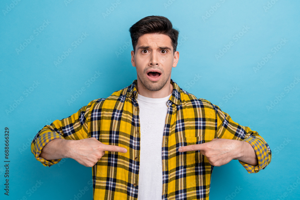 Photo of young frustrated speechless guy in checkered yellow shirt was found guilty point fingers himself isolated on blue color background Photo of young frustrated speechless guy in checkered yellow shirt was found guilty point fingers himself isolated on blue color background