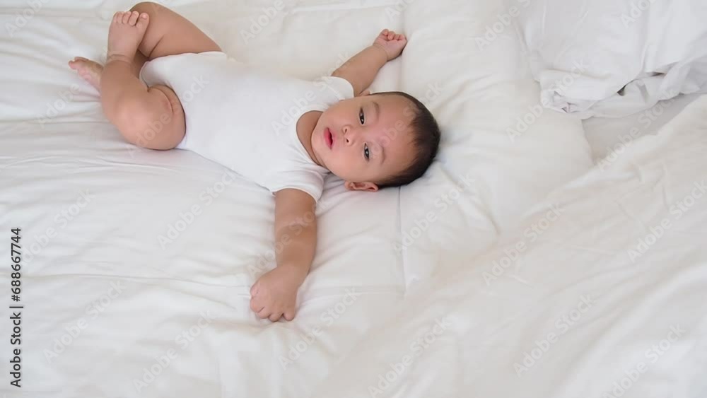lovely asian baby on dress with innocent actions on bed lovely asian baby on dress with innocent actions on bed