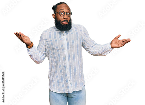 Young african american man wearing business shirt and glasses clueless and confused expression with arms and hands raised. doubt concept.