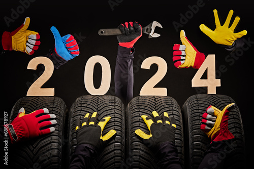 Winter car tires service and hands of mechanics, wrench and text 2024 happy new year on black background.