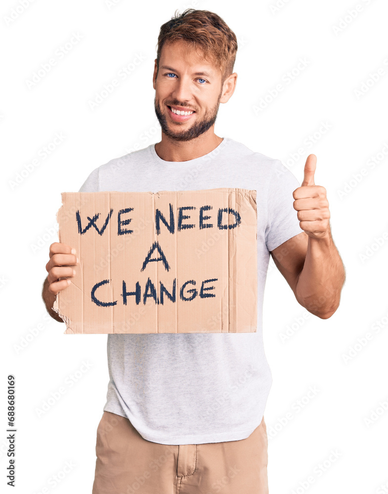 Young caucasian man holding we need a change banner smiling happy and positive, thumb up doing excellent and approval sign Young caucasian man holding we need a change banner smiling happy and positive, thumb up doing excellent and approval sign