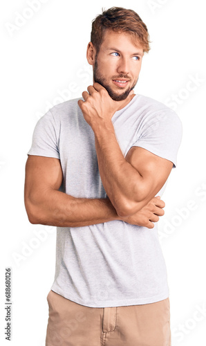 Young caucasian man wearing casual white tshirt with hand on chin thinking about question, pensive expression. smiling with thoughtful face. doubt concept.
