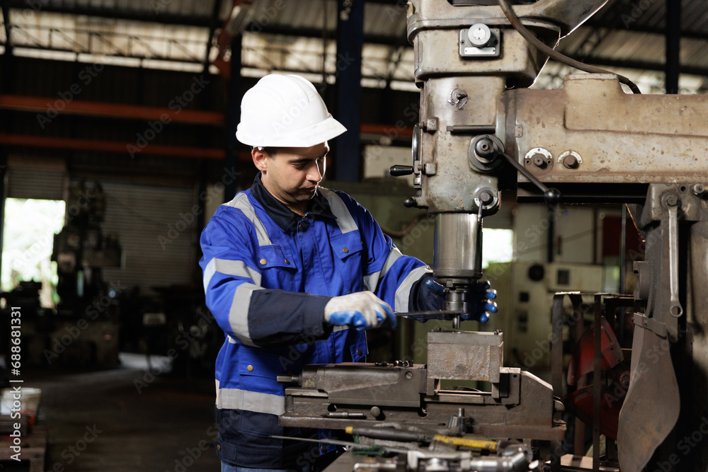 Male workers wearing uniform safety and hardhat working an iron cutting machine in factory. Engineering worker man work machine lathe metal. Male workers wearing uniform safety and hardhat working an iron cutting machine in factory. Engineering worker man work machine lathe metal.