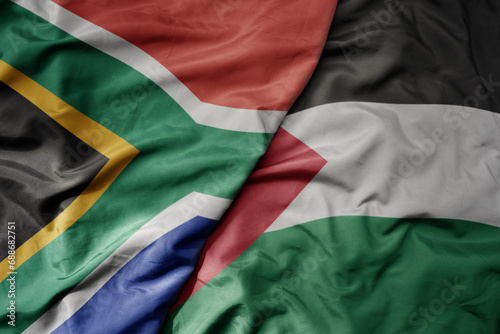 big waving national colorful flag of palestine and national flag of south africa .