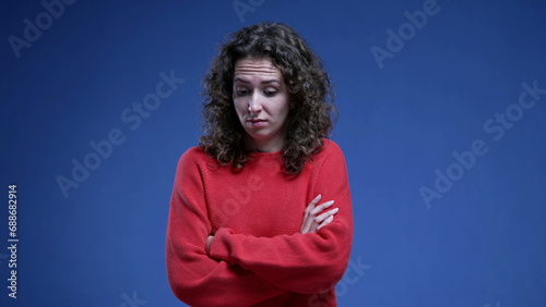 Woman feeling disgust and apprehension by crossing arms while feeling anxious and fearful standing on blue background, 20s female person in distraught stress emotion photo