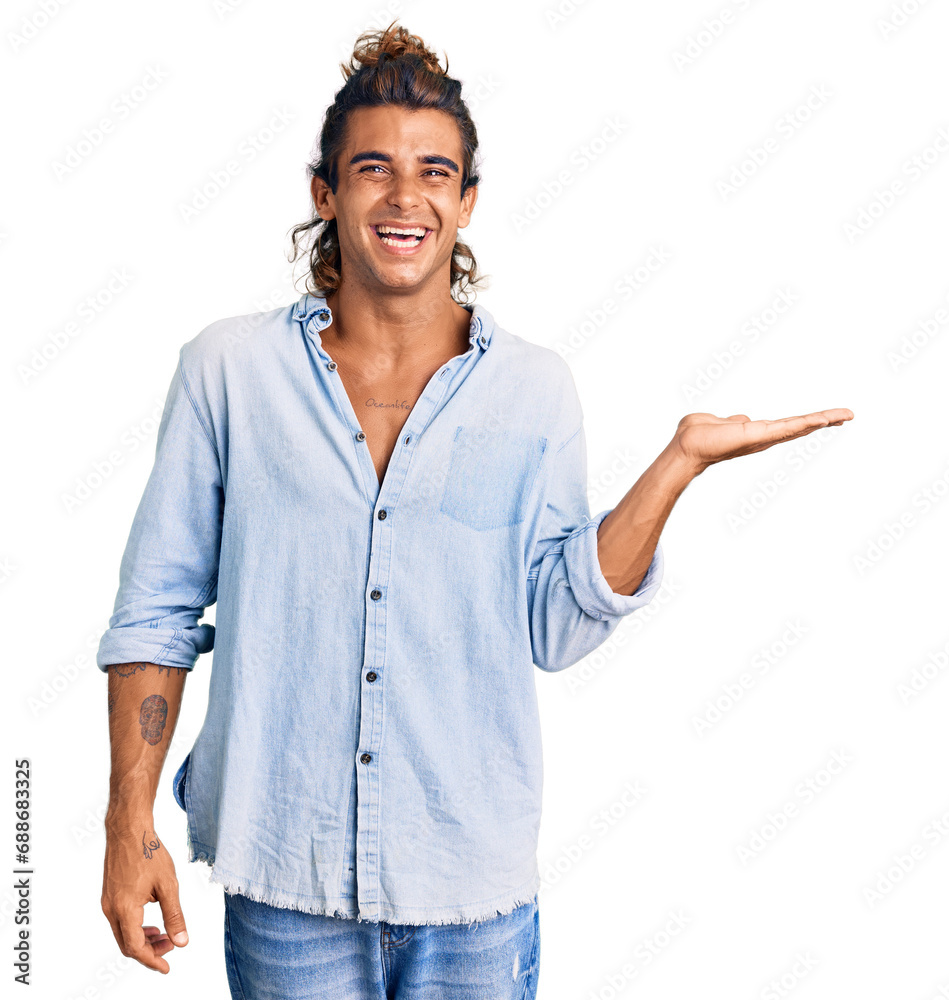 Young hispanic man wearing summer style smiling cheerful presenting and pointing with palm of hand looking at the camera. Young hispanic man wearing summer style smiling cheerful presenting and pointing with palm of hand looking at the camera.