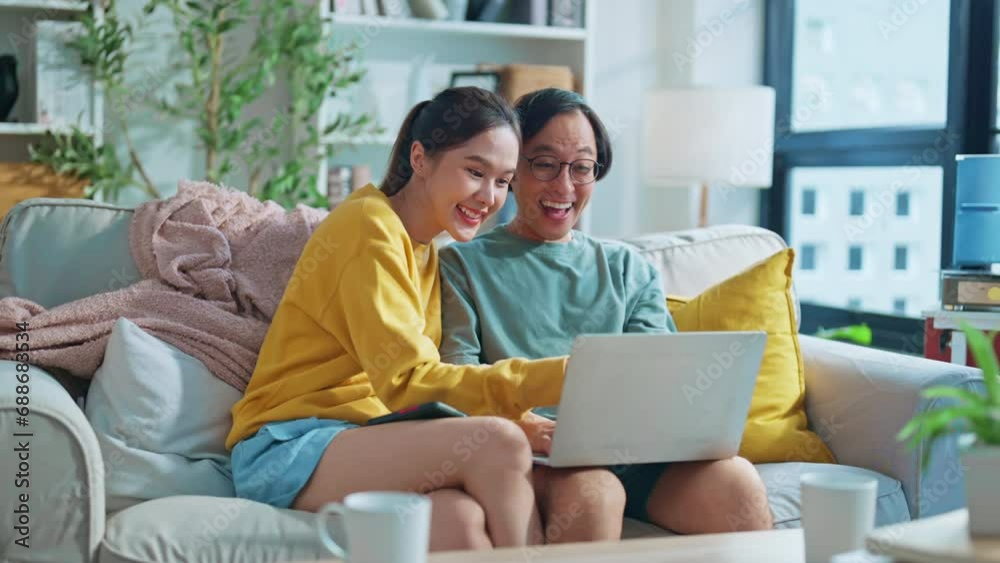sweet asian marry couple spending quality time together surfing internet social media online shopping hug positive conversation in living room at home family concept with smart technology at home