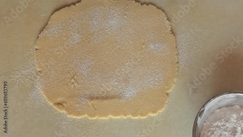 Rolling cake dough with a wooden rolling pin. Hands roll a piece of dough for pies, pizza, cakes, croissants. Close up. Concept of home baking