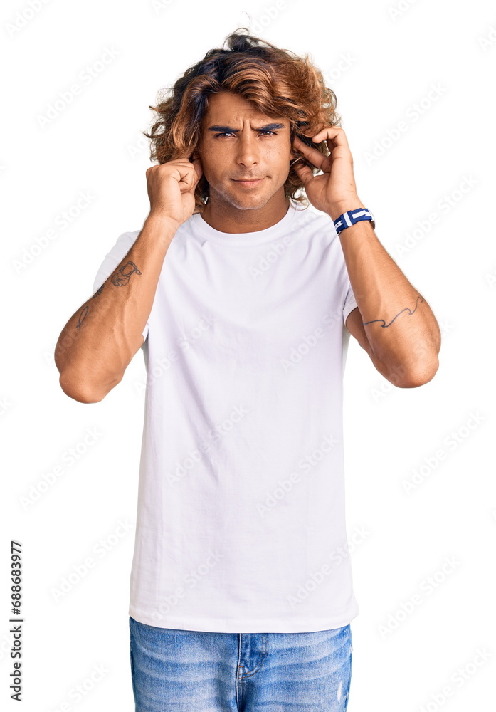 Young hispanic man wearing casual white tshirt covering ears with fingers with annoyed expression for the noise of loud music. deaf concept. Young hispanic man wearing casual white tshirt covering ears with fingers with annoyed expression for the noise of loud music. deaf concept.