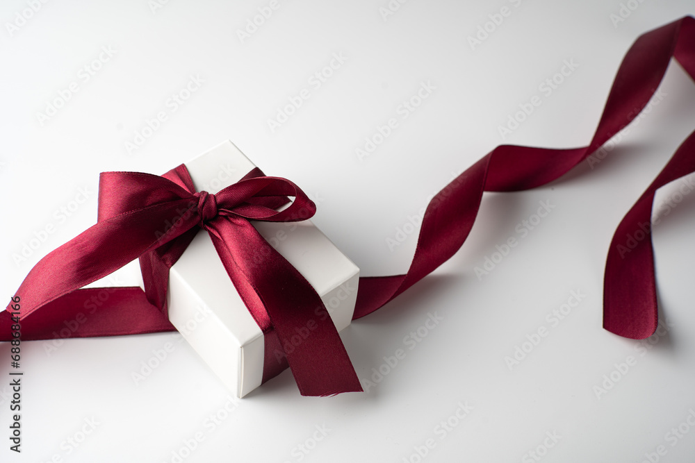White gift box with red bow on white background with red hearts. Holiday banner. Top view. Happy Valentines Day