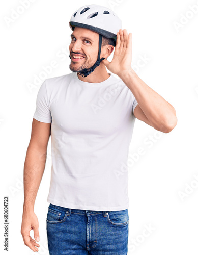 Young handsome man wearing bike helmet smiling with hand over ear listening an hearing to rumor or gossip. deafness concept.