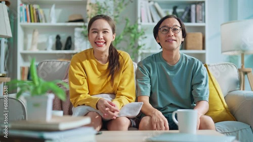 funny humor family moment asian marry love couple family enjoy watch tv comedy show on tv in sunday morning weekend on sofa embrace sweet relation positive vibes they laugh together on sofa at home photo