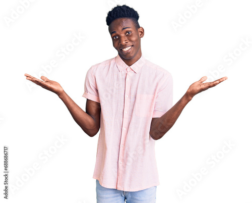 Young african american man wearing casual clothes clueless and confused expression with arms and hands raised. doubt concept.