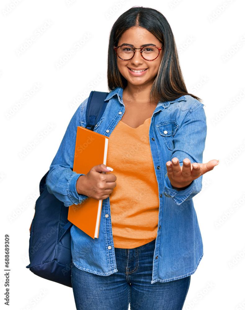 Young latin girl wearing student backpack and holding books smiling cheerful offering palm hand giving assistance and acceptance. Young latin girl wearing student backpack and holding books smiling cheerful offering palm hand giving assistance and acceptance.